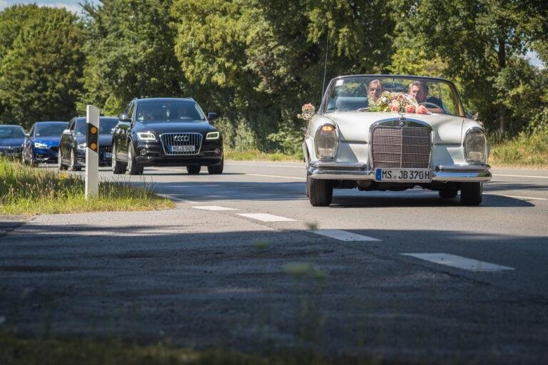 Weißer Oldtimer fährt das Brautpaar über die Landstraße – Hochzeitsfeier Miriam & Pascal