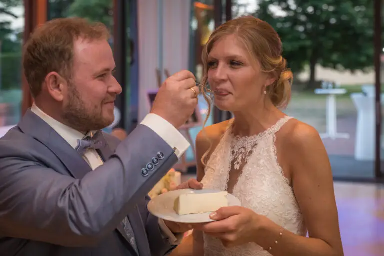 Brautpaar füttert sich gegenseitig mit Hochzeitstorte – Hochzeitsfeier Miriam & Pascal