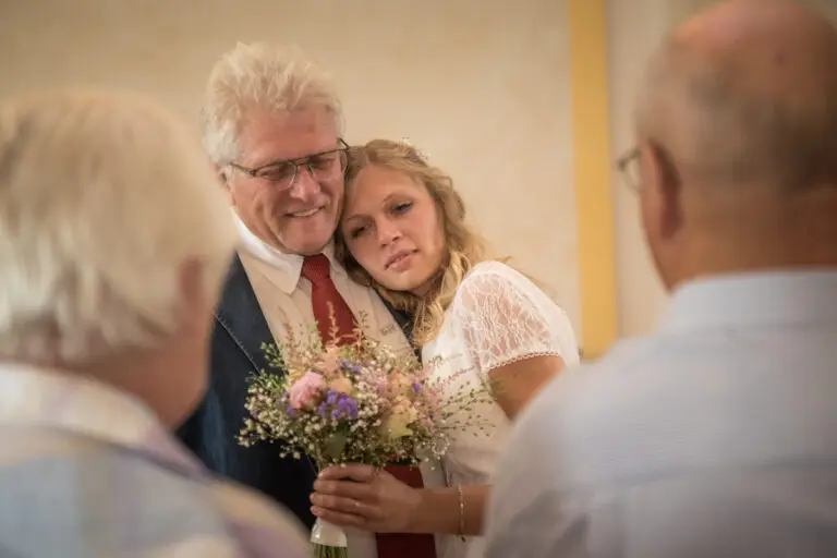 Braut mit Brautstrauß wird von einem älteren Mann umarmt – Hochzeit Miriam & Pascal