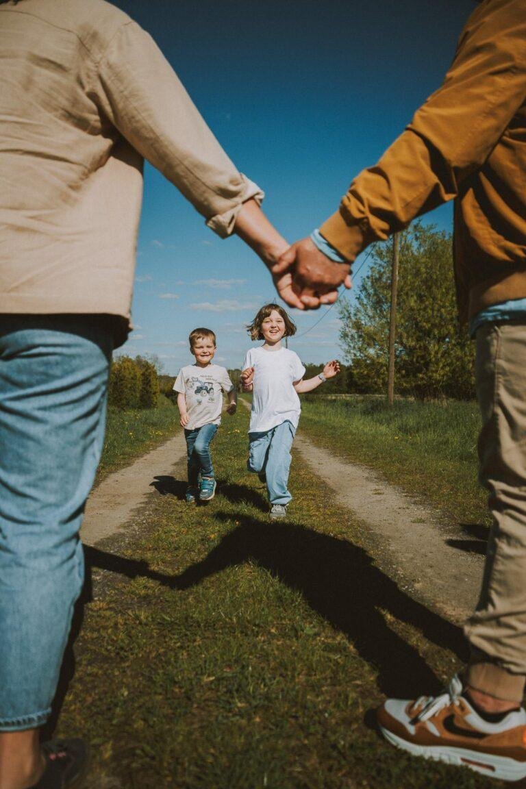 Web-1-3 Familie läuft Hand in Hand über einen Feldweg – Familienfotografie von SNDR Photos