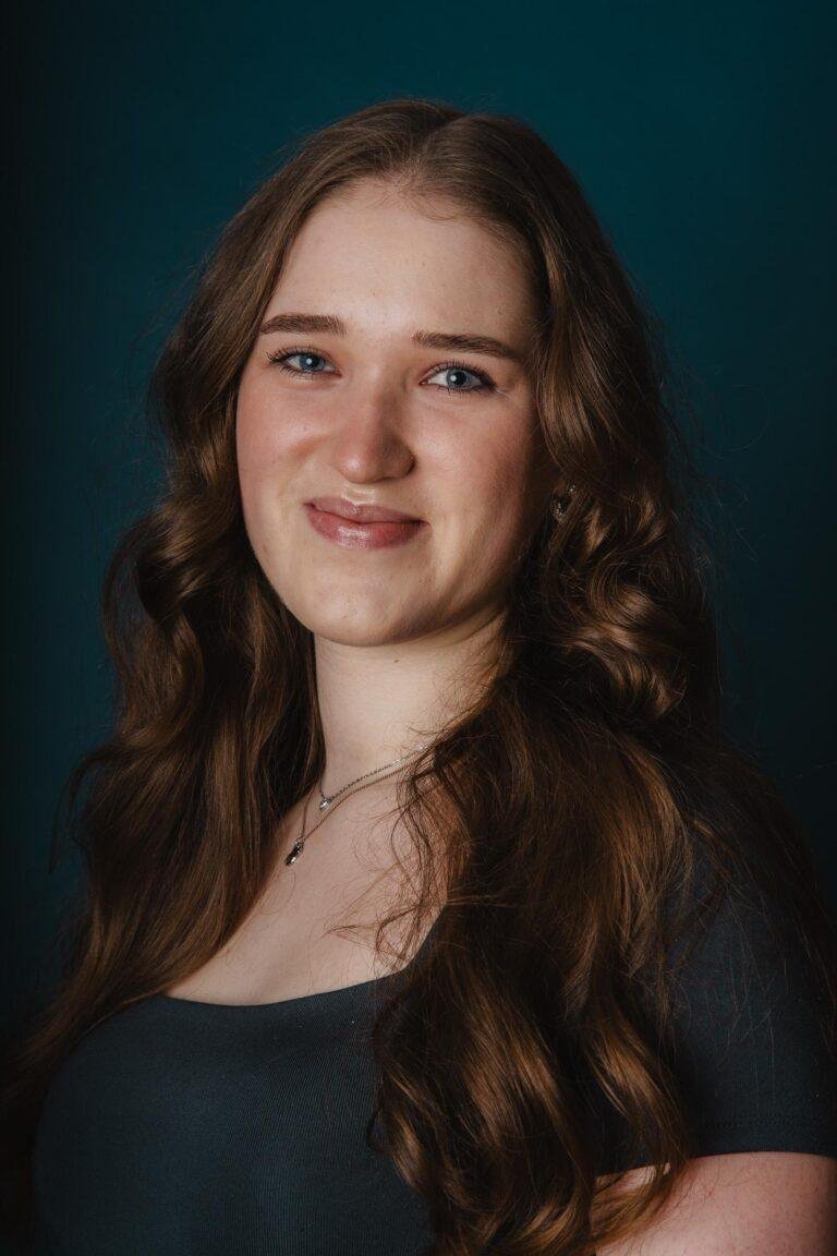Portrait einer jungen Frau mit langen Haaren vor dunklem Hintergrund – Portraitfotografie Münster