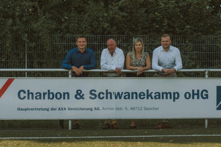 Team hinter einem Bandenbanner auf dem Sportplatz – Business-Fotografie SNDR Photos Münster
