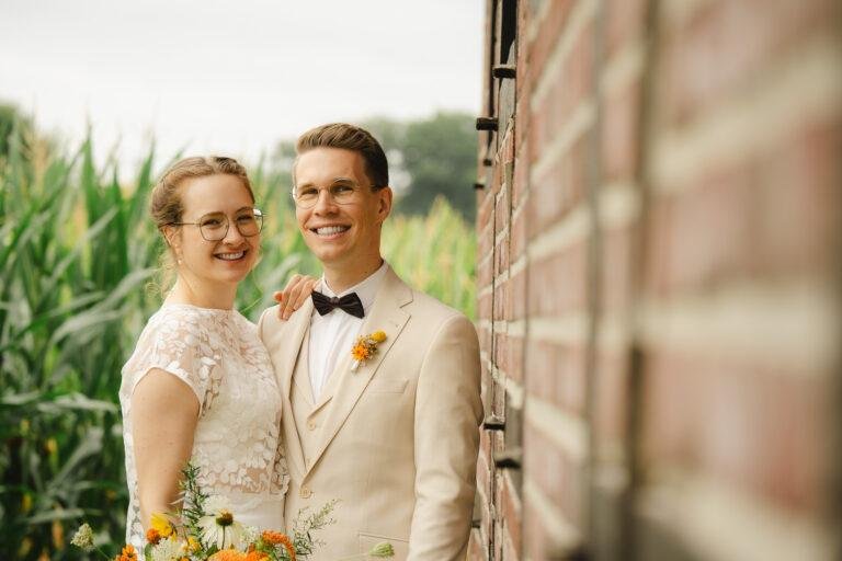 Braut und Bräutigam lachen vor einer Backsteinwand – Brautpaarshooting Nora & Simon