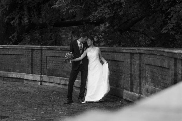 Web-15 Schwarz-Weiß-Foto: Brautpaar an einer Steinmauer – Brautpaarshooting Bernadette & André am Schloss Münster
