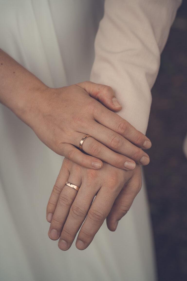 Nahaufnahme der Hände mit Eheringen auf dem Brautkleid – Brautpaarshooting Nora & Simon
