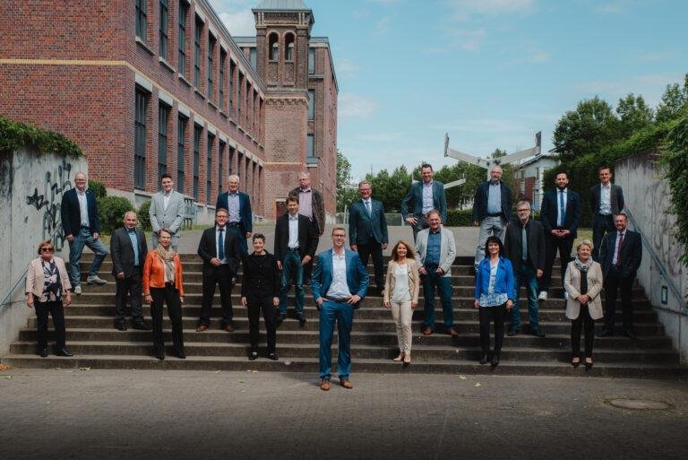 Großes Firmenteam auf einer Treppe vor einem Backsteingebäude – Business-Fotografie SNDR Photos Münster