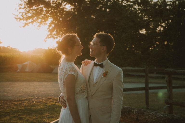Braut und Bräutigam schauen sich im Sonnenuntergang verliebt an – Brautpaarshooting Nora & Simon