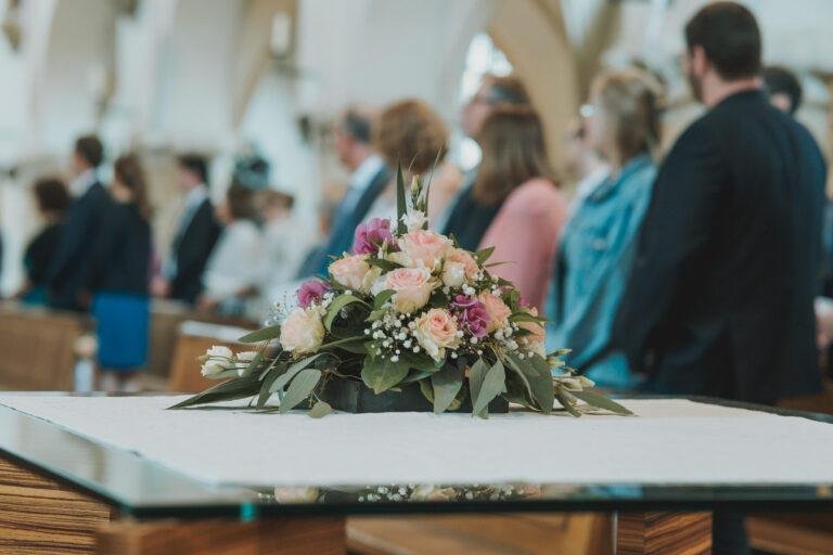 Web-19 Brautstrauß auf dem Altar, Gäste im Hintergrund – kirchliche Trauung Bernadette & André