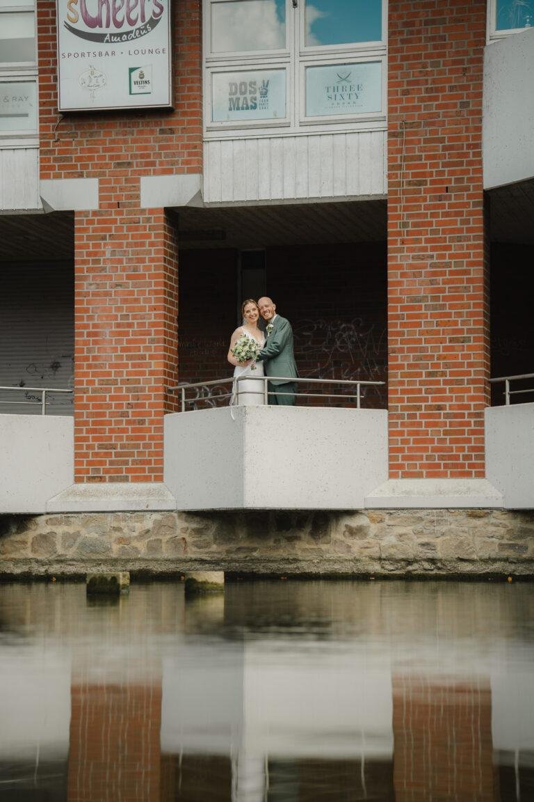 Web-2 Brautpaar steht auf einem Steg, gespiegelt im Wasser – Brautpaarshooting Renée & Patrick