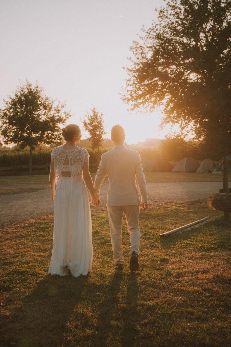 Braut und Bräutigam gehen bei Sonnenuntergang Hand in Hand – Brautpaarshooting Nora & Simon