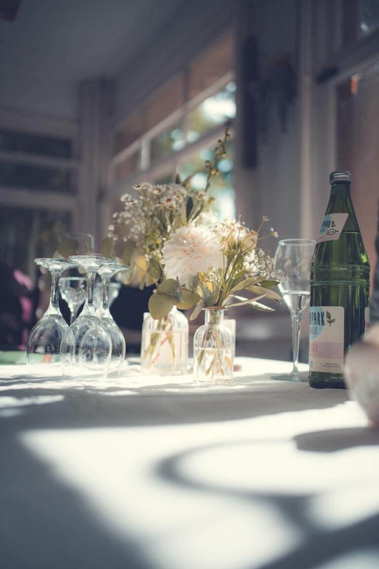 Web-22 Gedeckter Tisch mit Gläsern und Blumen im Sonnenlicht – Hochzeitsfeier Renée & Patrick im Café Nobis