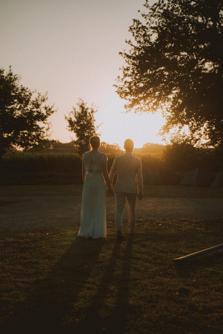 Brautpaar steht in der tiefstehenden Abendsonne auf einem Feldweg – Brautpaarshooting Nora & Simon