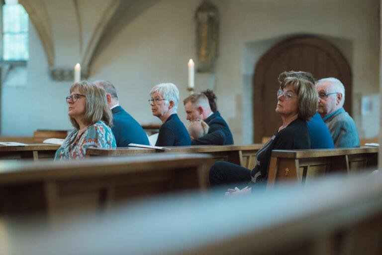 Web-28 Gäste sitzen in den Kirchenbänken – kirchliche Trauung Bernadette & André