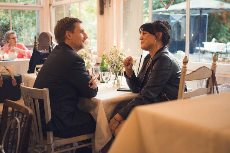 Web-29 Gäste unterhalten sich am Tisch am Fenster – Hochzeitsfeier Renée & Patrick im Café Nobis