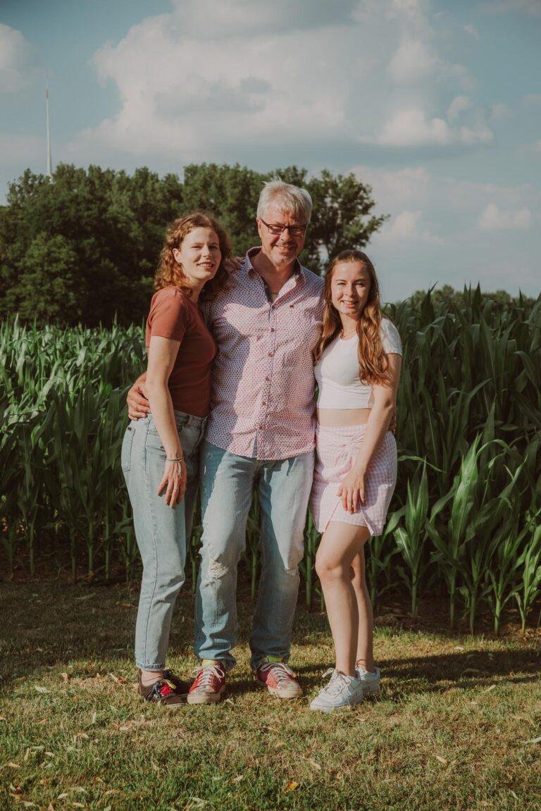 Eltern mit erwachsener Tochter vor einem Maisfeld – Familienfotoshooting SNDR Photos Münster