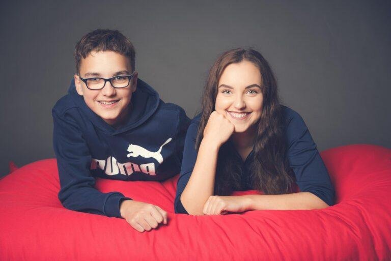 Zwei Geschwister liegen lachend auf einem roten Sitzsack – Familienfotoshooting SNDR Photos Münster