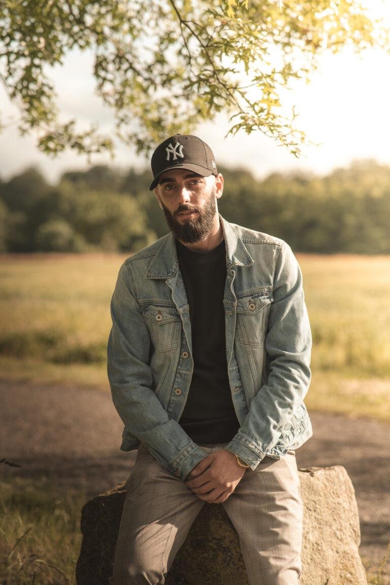 Mann sitzt draußen im Grünen – Outdoor-Portrait von SNDR Photos