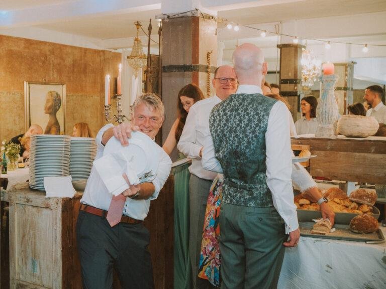 Web-30 Bräutigam umarmt einen Gast am Buffet – Hochzeitsfeier Renée & Patrick im Café Nobis