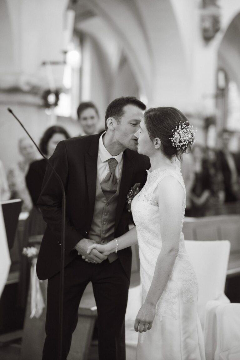 Web-33 Schwarz-Weiß-Foto: Brautpaar küsst sich in der Kirche – kirchliche Trauung Bernadette & André
