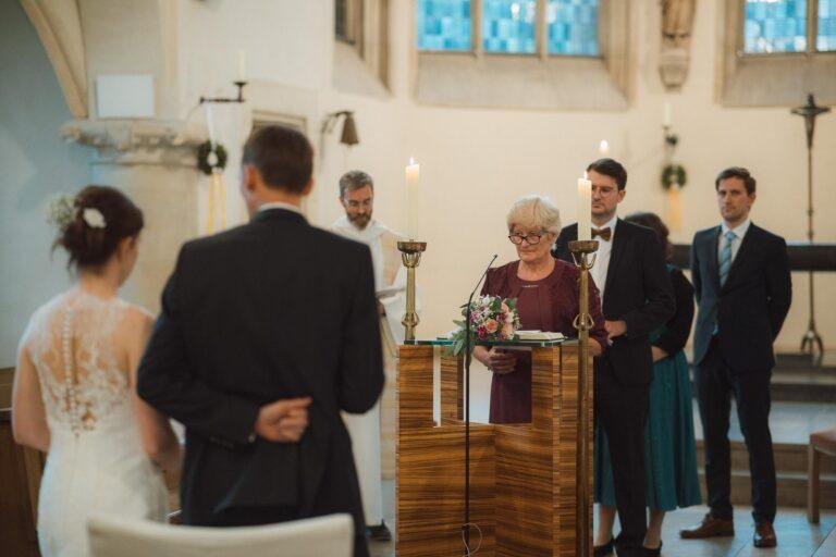 Web-36 Brautpaar steht vor dem Altar, Blick aus den Bänken – kirchliche Trauung Bernadette & André