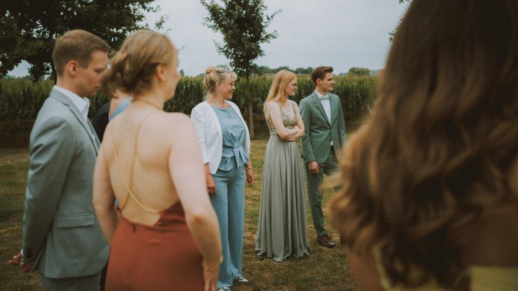 Gäste stehen nach der Trauung auf einer Wiese zusammen – Hochzeitsreportage SNDR Photos Münster