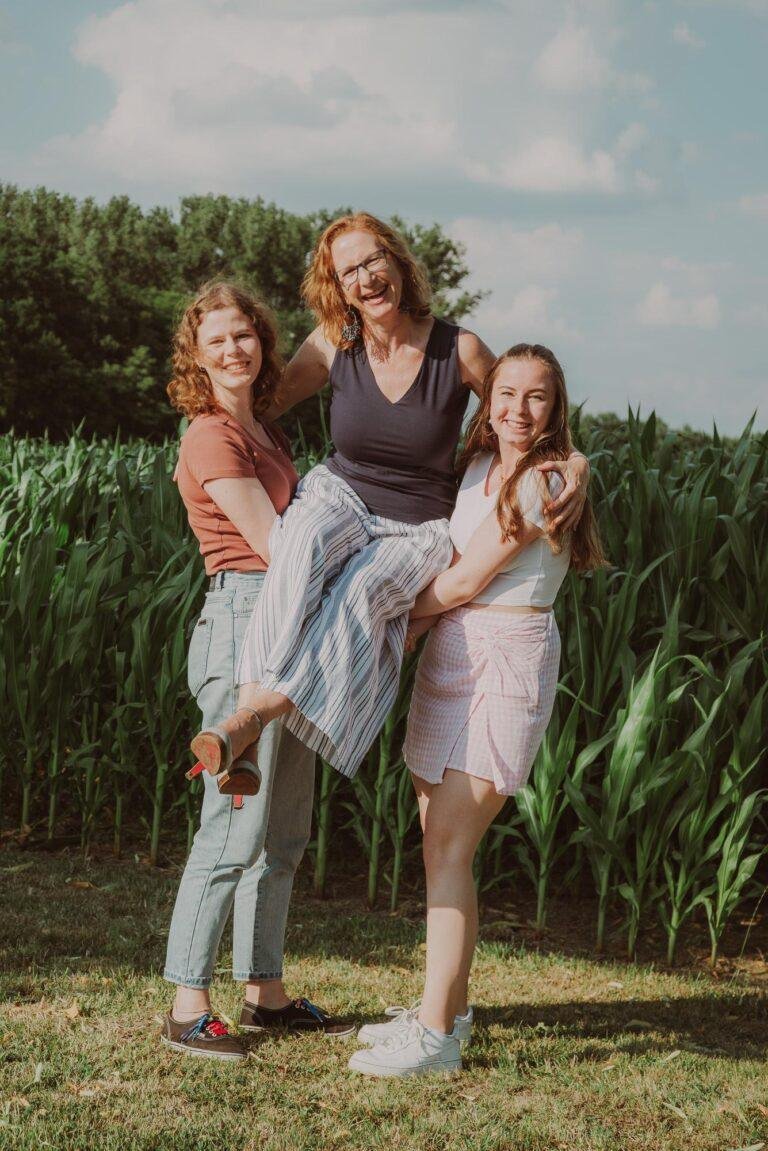 Mutter mit zwei Töchtern lacht vor einem Maisfeld – Familienfotoshooting SNDR Photos Münster