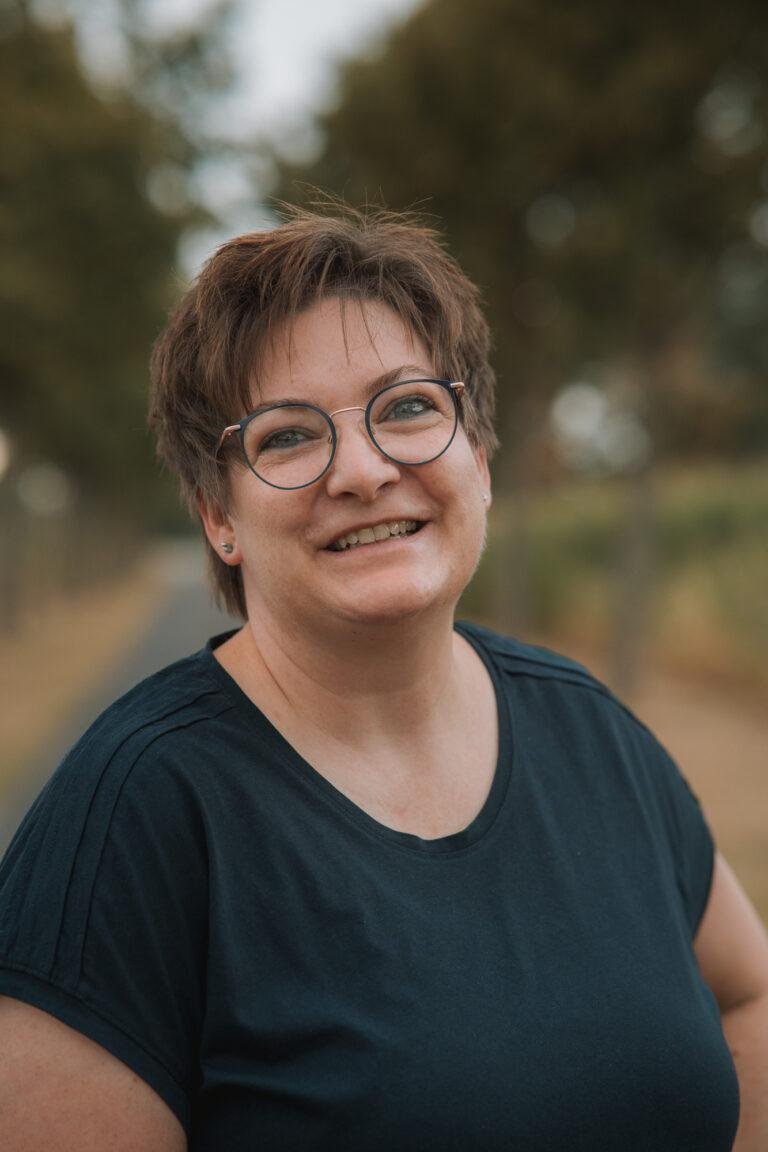 Frau mit Brille lächelt im Freien – Portraitfotos SNDR Photos Münster