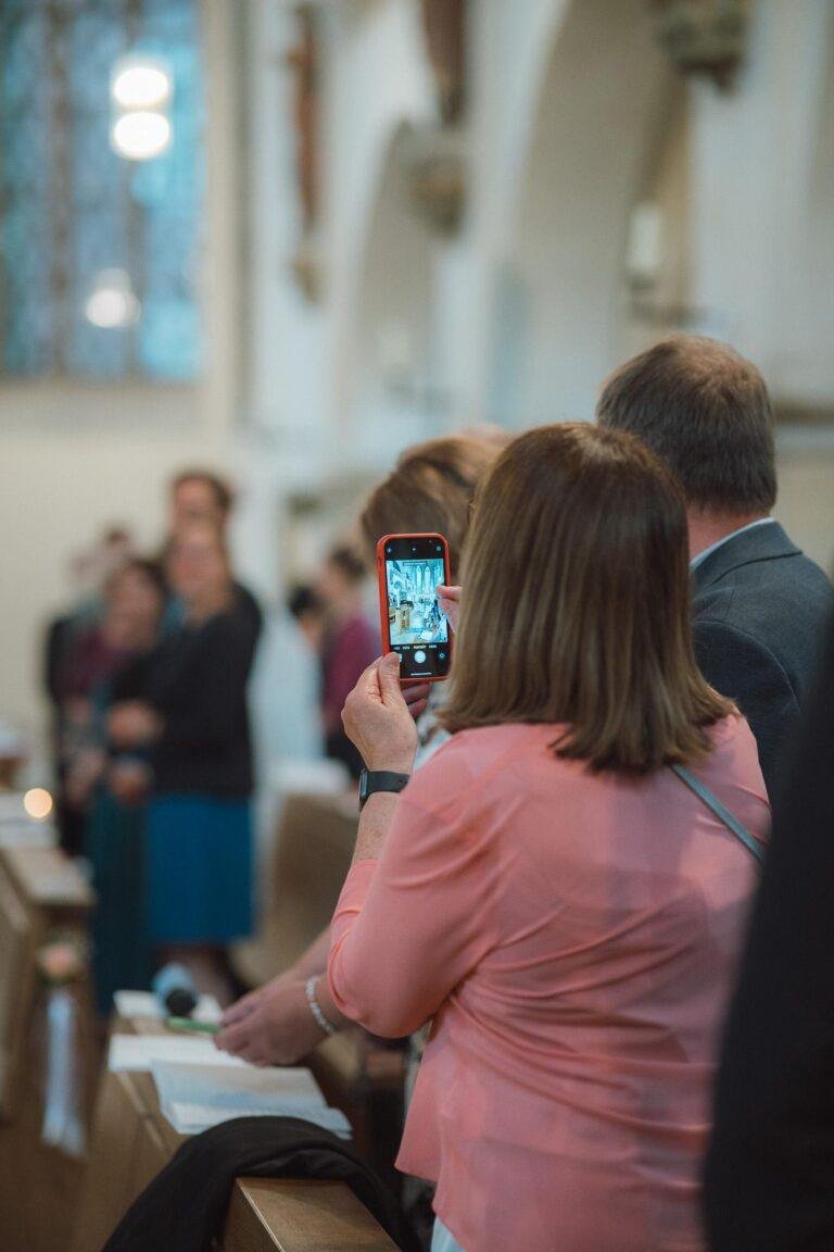 Web-40 Gast fotografiert die Trauung mit dem Handy – kirchliche Trauung Bernadette & André