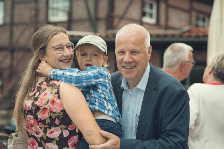 Älterer Mann umarmt lachend ein Kind – Hochzeitsfeier Nora & Simon