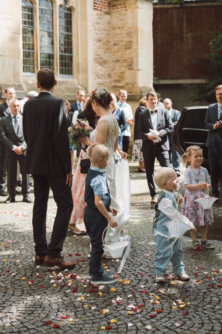 Web-46 Gäste und Kinder warten vor der Kirche – kirchliche Trauung Bernadette & André