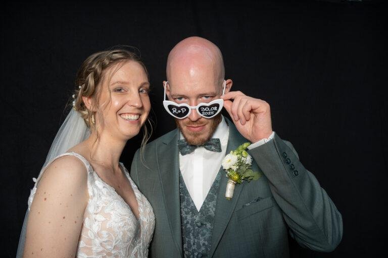 Web-47 Brautpaar mit lustiger Brille vor schwarzem Hintergrund – Hochzeit Renée & Patrick, Fotobox-Porträt