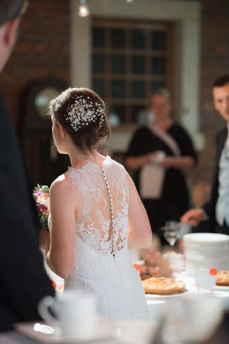 Web-49 Braut mit Haarschmuck am Kuchenbuffet, Rückenansicht – Hochzeitsfeier Bernadette & André