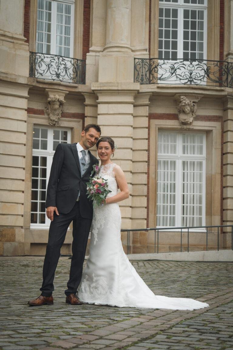 Web-5 Brautpaar vor der Sandsteinfassade des Schlosses – Brautpaarshooting Bernadette & André am Schloss Münster
