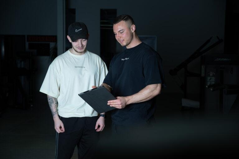Trainer bespricht mit einem Kunden einen Trainingsplan – Business-Fotografie SNDR Photos Münster