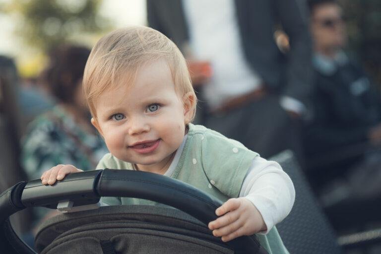 Kleiner Junge schaut fröhlich aus einem Kinderwagen – Hochzeitsfeier Nora & Simon