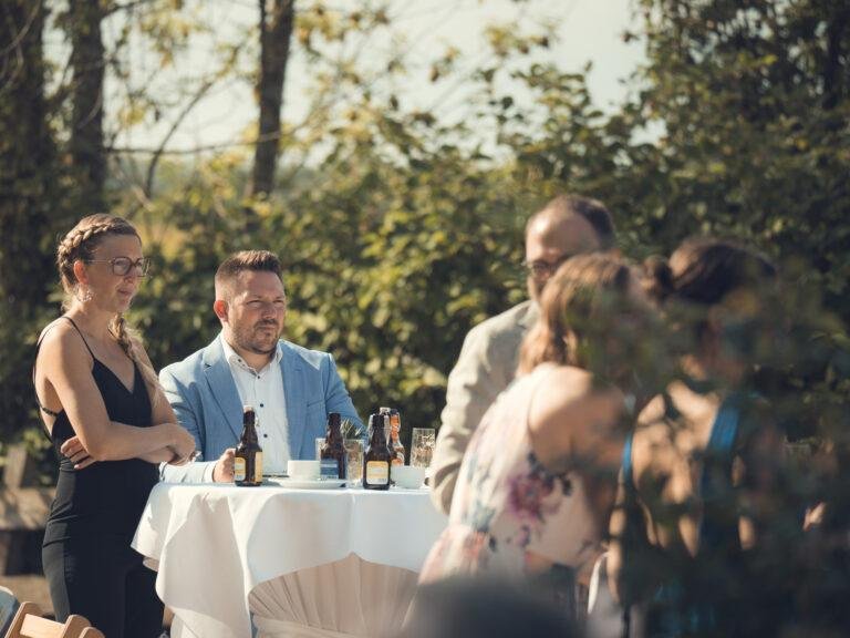 Gäste sitzen an weiß gedeckten Tischen im Garten – Hochzeitsfeier Nora & Simon
