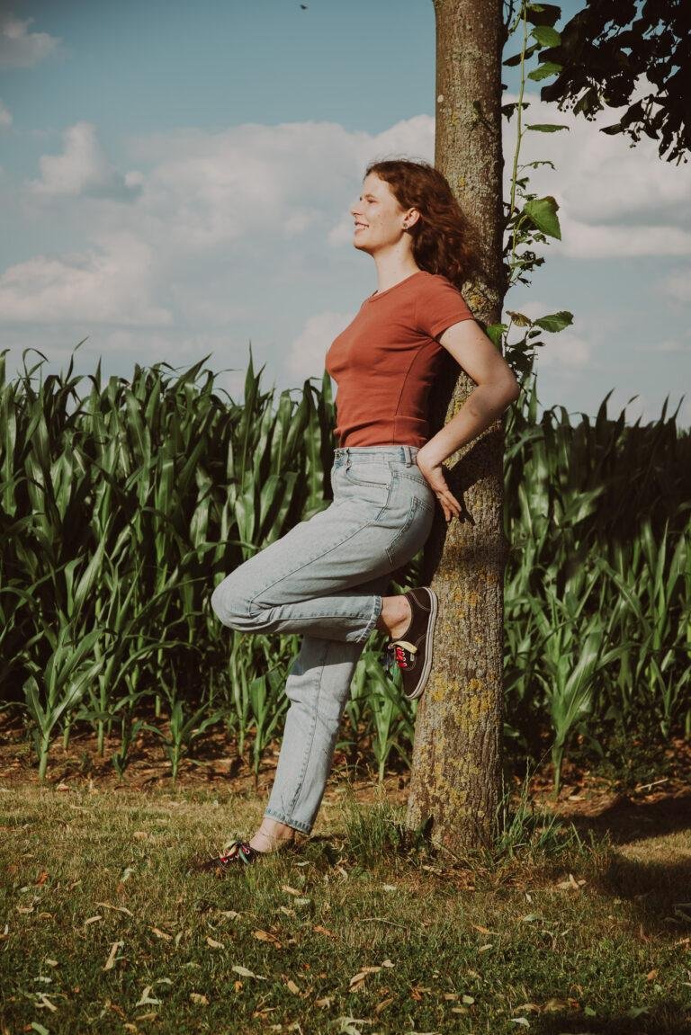 Junge Frau lehnt an einem Baum am Feldrand – Outdoor-Portrait Münster