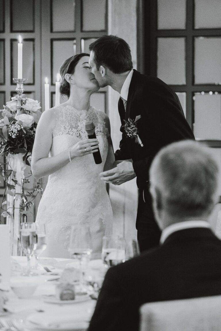 Web-72 Schwarz-Weiß-Foto: Brautpaar küsst sich während der Rede – Hochzeitsfeier Bernadette & André