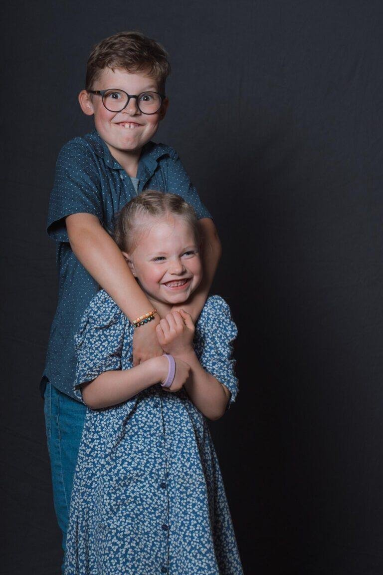 Web-75 Zwei Kinder posieren lachend vor dunklem Hintergrund – Hochzeitsfeier Bernadette & André