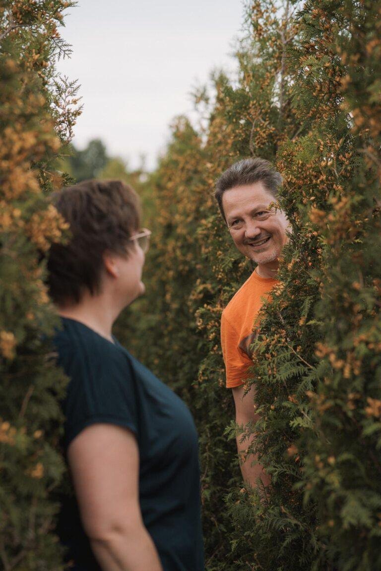 Paar steht sich vor einer grünen Hecke gegenüber – Paarfotografie SNDR Photos
