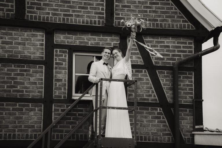 Schwarz-Weiß-Foto: Brautpaar auf der Treppe eines Fachwerkhauses – Brautpaarshooting Nora & Simon