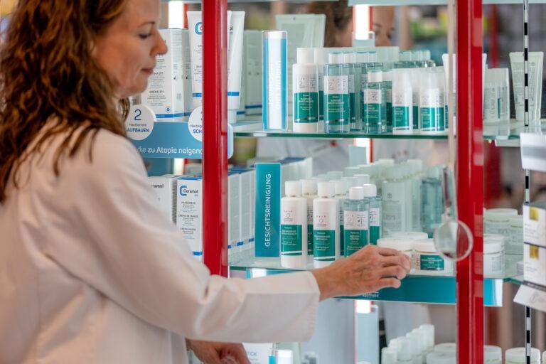 Apothekerin greift ins Regal mit Pflegeprodukten – Business-Fotografie SNDR Photos Münster