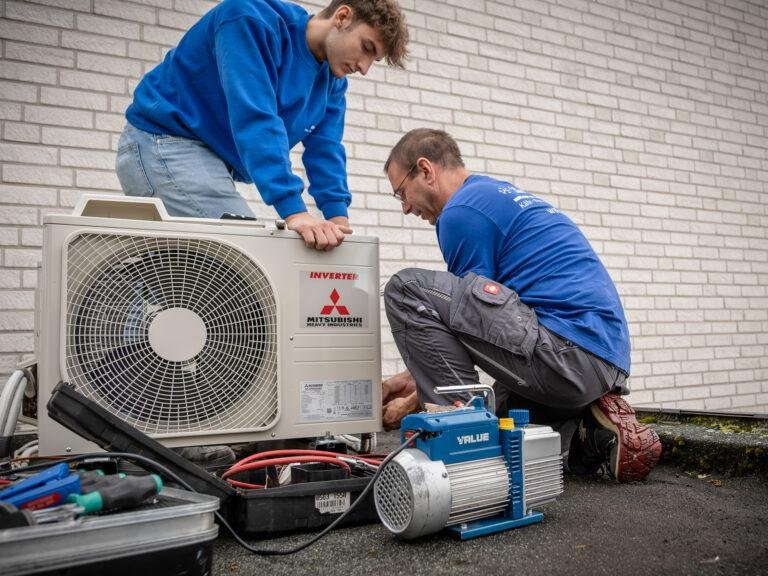 Zwei Techniker montieren eine Klimaanlage an einer Hauswand – Business-Fotografie SNDR Photos Münster
