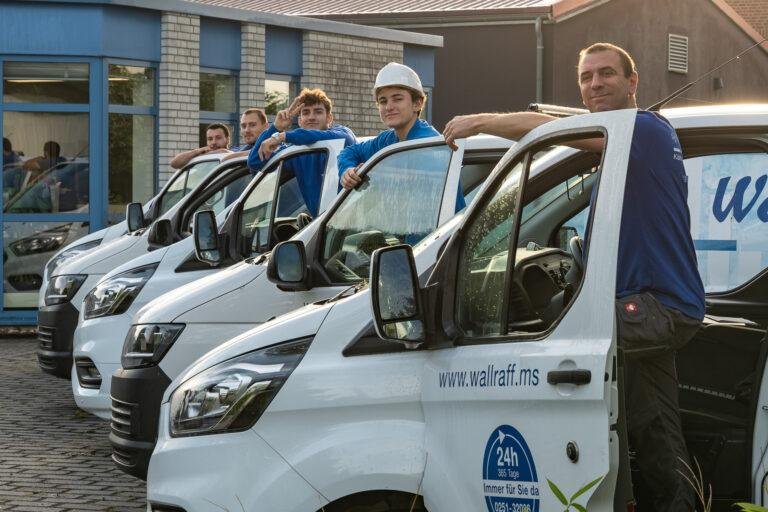 Team steht vor einer Reihe weißer Firmenwagen – Business-Fotografie SNDR Photos Münster