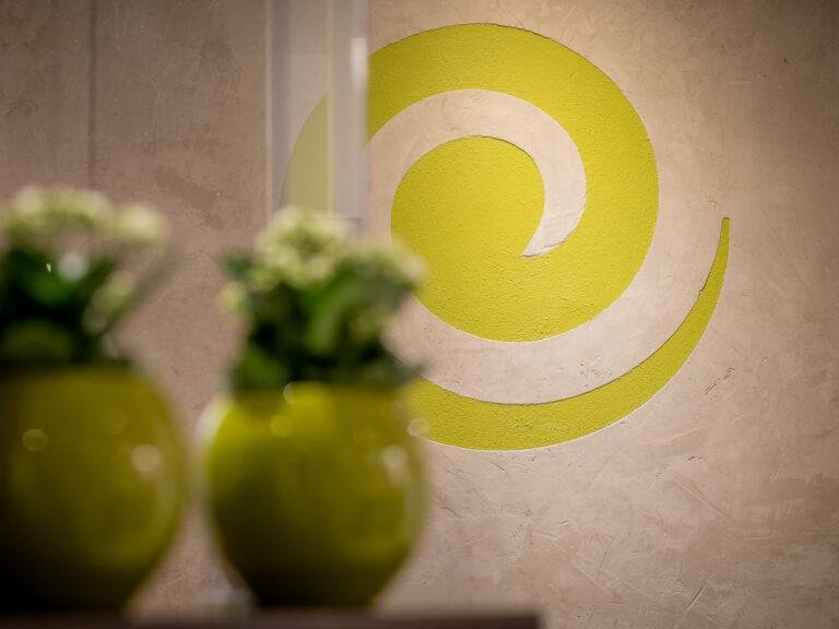 Grüne Vasen mit weißen Blumen vor dem Firmenlogo – Business-Fotografie SNDR Photos Münster
