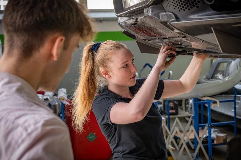 Mechanikerin und Kunde unter einem Auto auf der Hebebühne – Business-Fotografie SNDR Photos Münster
