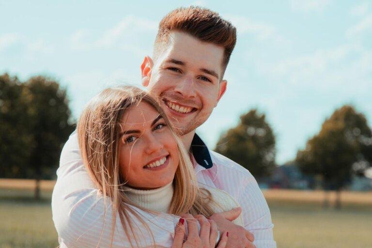 Junges Paar umarmt sich lachend auf einer Wiese – Heiratsantrag fotografieren lassen in Münster